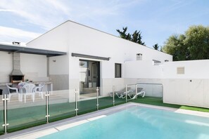 Een modern huis met een zwembad, buiten zitplaatsen en een barbecueplek.