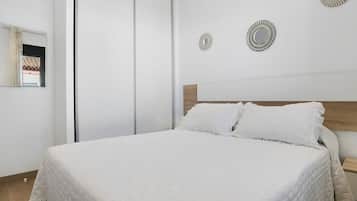 A bedroom with a bed, a wooden headboard, and two wall-mounted decorative mirrors.