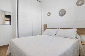 A bedroom with a bed, a wooden headboard, and two wall-mounted decorative mirrors. - Holiday Home 'Casas Las Arenas 1' with Private Saltwater Pool, Wi-Fi and Air Conditioning (Conil de la Frontera)