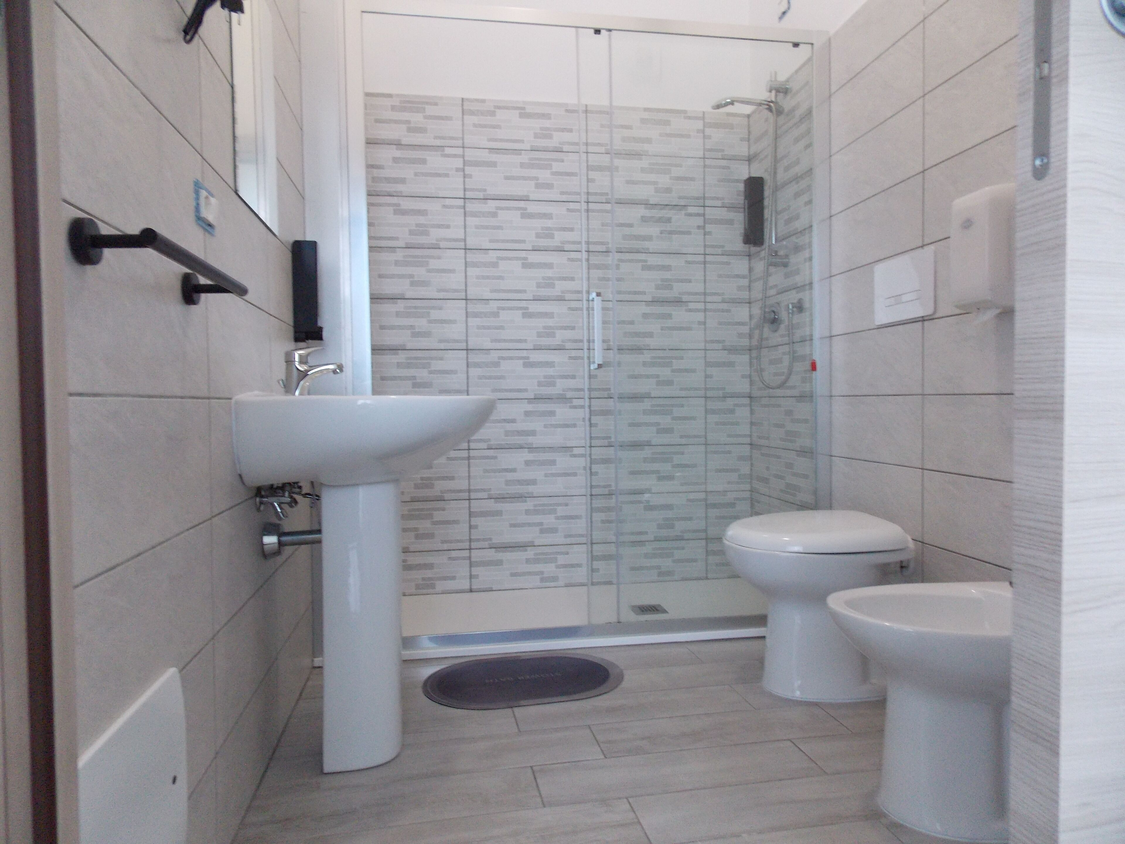 A modern bathroom with a glass-enclosed shower, a white sink, and a toilet.