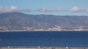 A coastal cityscape with a clear view of the ocean and distant mountains. - Central Palace (Reggio Calabria)
