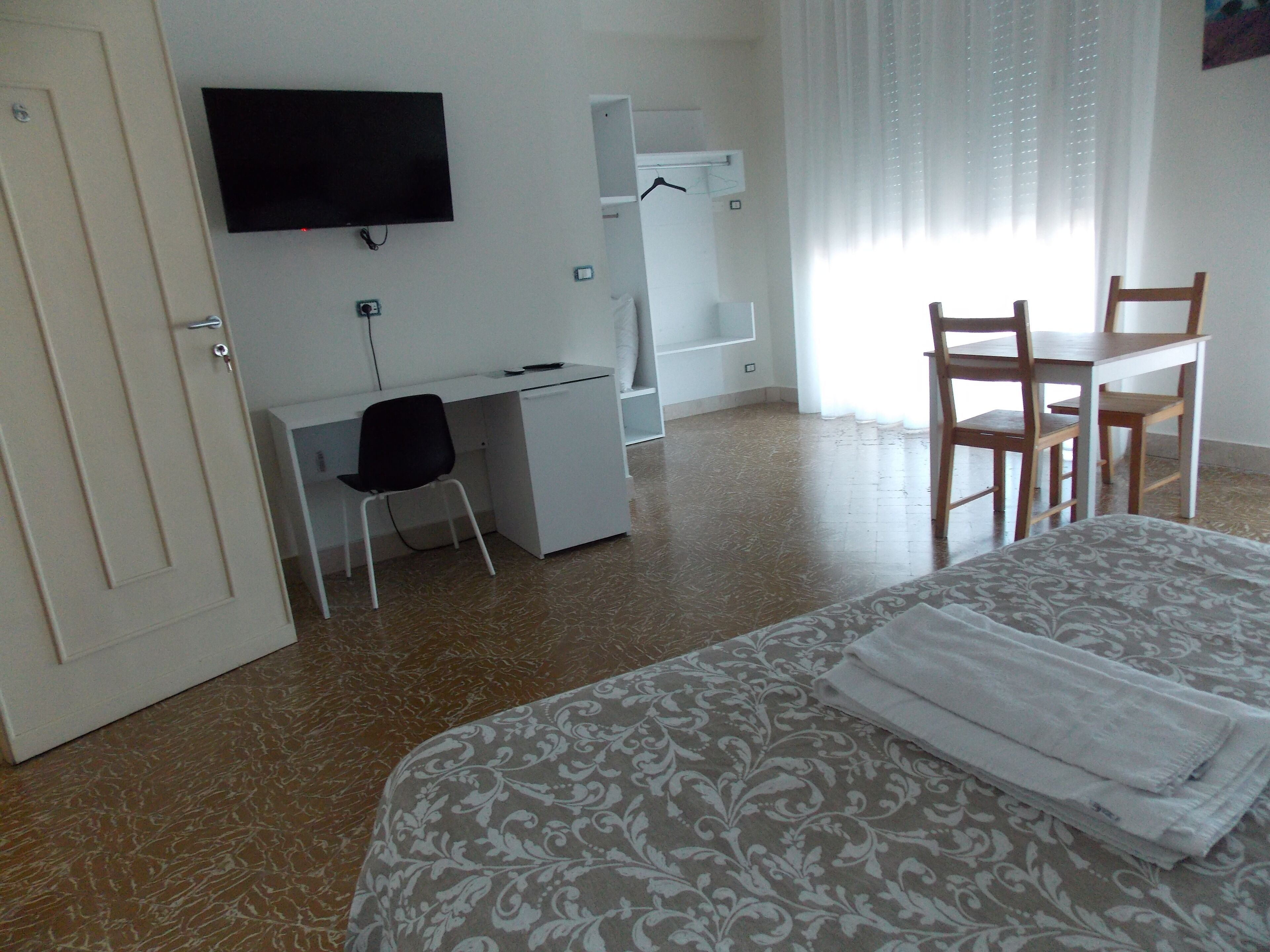 Une chambre d’hôtel comprenant un lit, un bureau avec une chaise, une télévision et une armoire.