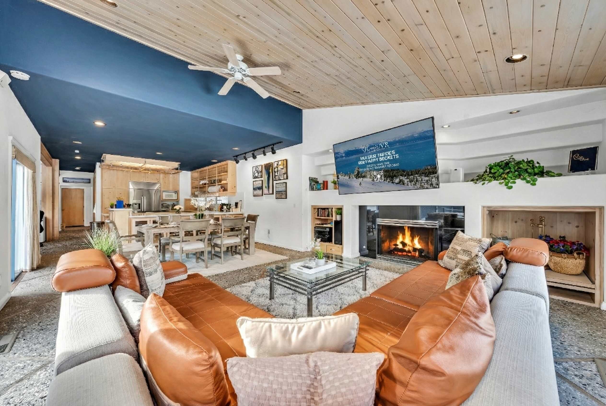 A modern living room with leather sofas, a glass coffee table, a fireplace, and a television mounted on the wall.