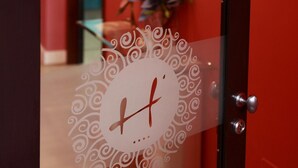 Una puerta con un panel de vidrio decorativo que presenta una letra 'H' estilizada y un diseño circular.
