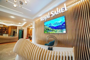 A reception area with a large TV displaying a scenic landscape, a reception desk, and a modern, striped wall design.