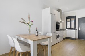 Eine moderne Küche mit weißen Schränken, einem Holztisch und zwei weißen Stühlen.
