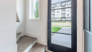 En moderne lejlighedstand med en sort dør, et lille vindue og udsigt til en høj bygning.