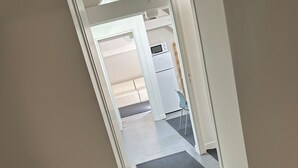 Eteisessä on musta matto, ja se johtaa keittiötilaan, jossa on mikroaaltouuni ja jääkaappi.