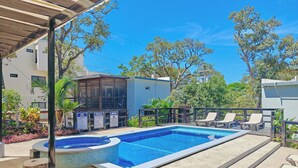 Une piscine avec des chaises longues, un jacuzzi et un espace abrité agrémenté d’une pergola.
