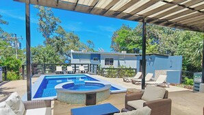 Un espace extérieur abrité comprenant une piscine, des chaises longues et des meubles en osier.