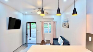 Une chambre moderne équipée d’un téléviseur à écran plat, d’un ventilateur de plafond, d’une table à manger et d’un canapé avec un coussin.