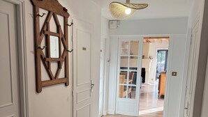 Een gang met houten vloer, witte deuren en een hangende lamp.