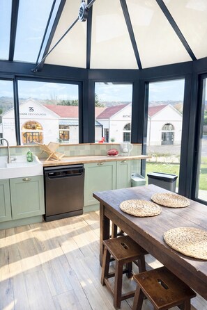 Une cuisine moderne avec une grande fenêtre, une table en bois et des armoires vertes.