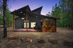 Eine moderne Blockhütte mit großer Terrasse, einem überdachten Außenbereich zum Sitzen und einem auffälligen Holzwand-Design.
