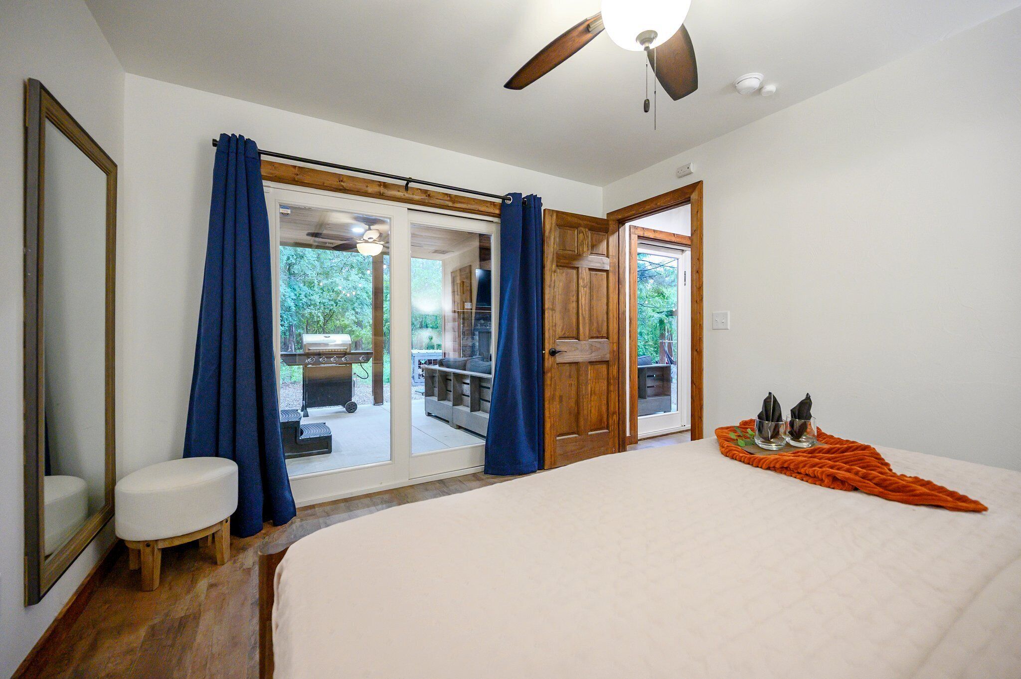 Un dormitorio con una cama grande, un ventilador de techo y vistas a una terraza exterior.