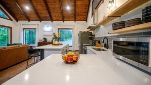 Una cocina moderna con una isla grande, vigas de techo de madera y vistas al exterior.