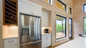 Una cucina moderna con elettrodomestici in acciaio inox, mobili bianchi e ampie finestre che offrono vista sull'esterno.