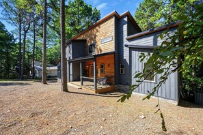 Een chalet met twee verdiepingen, een houten terras en een garage.