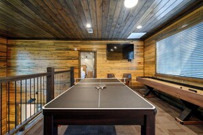 Una mesa de ping pong en una habitación con paredes de madera y una ventana.