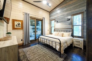 Un dormitorio con una cama, una mesita de noche, un aparador, una ventana y un ventilador de techo.