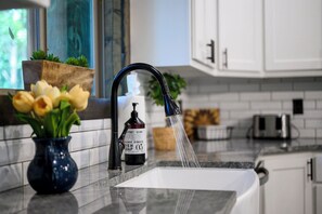 A kitchen with a modern faucet, a vase with flowers, and a bottle of dish soap. - Luxurious 4 Bedroom Cabin Retreat in Broken Bow (Broken Bow)