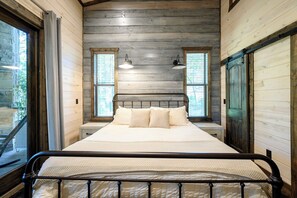A bed in a room with wooden walls, two windows with blinds, and a metal headboard. - Luxurious 4 Bedroom Cabin Retreat in Broken Bow (Broken Bow)