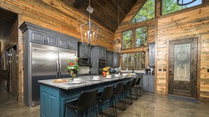 Une cuisine moderne dotée d’un grand îlot central, d’appareils électroménagers en acier inoxydable et d’un intérieur au style rustique avec des éléments en bois.
