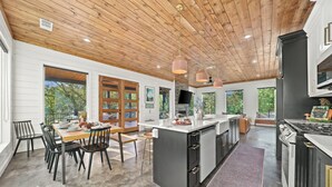 Una cocina amplia con una isla grande, techo de madera y abundante luz natural que entra por ventanas grandes.