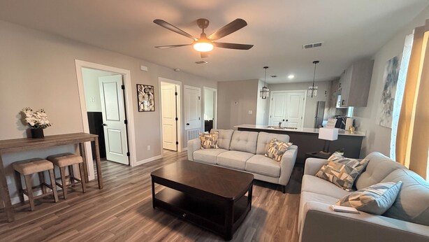 A modern living room with a sofa, coffee table, and a dining area with stools. - Executive Comfort Suite (Weslaco)