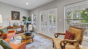 A spacious living room with a large window, a glass coffee table, and comfortable seating. - 5BR Estate • Hot Tub & Sleeps 10 • Near Beach (Edgewater)
