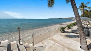 A beach with a clear view of the sea, a pebble beach, and a palm tree. - Panarea 1B | Beachfront 3BR + Direct Ocean Views, Sleeps 6 & Resort Pools (Bucerías)