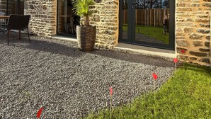 A stone building with large windows and a gravel patio. - Ecrin de charme (Granville)