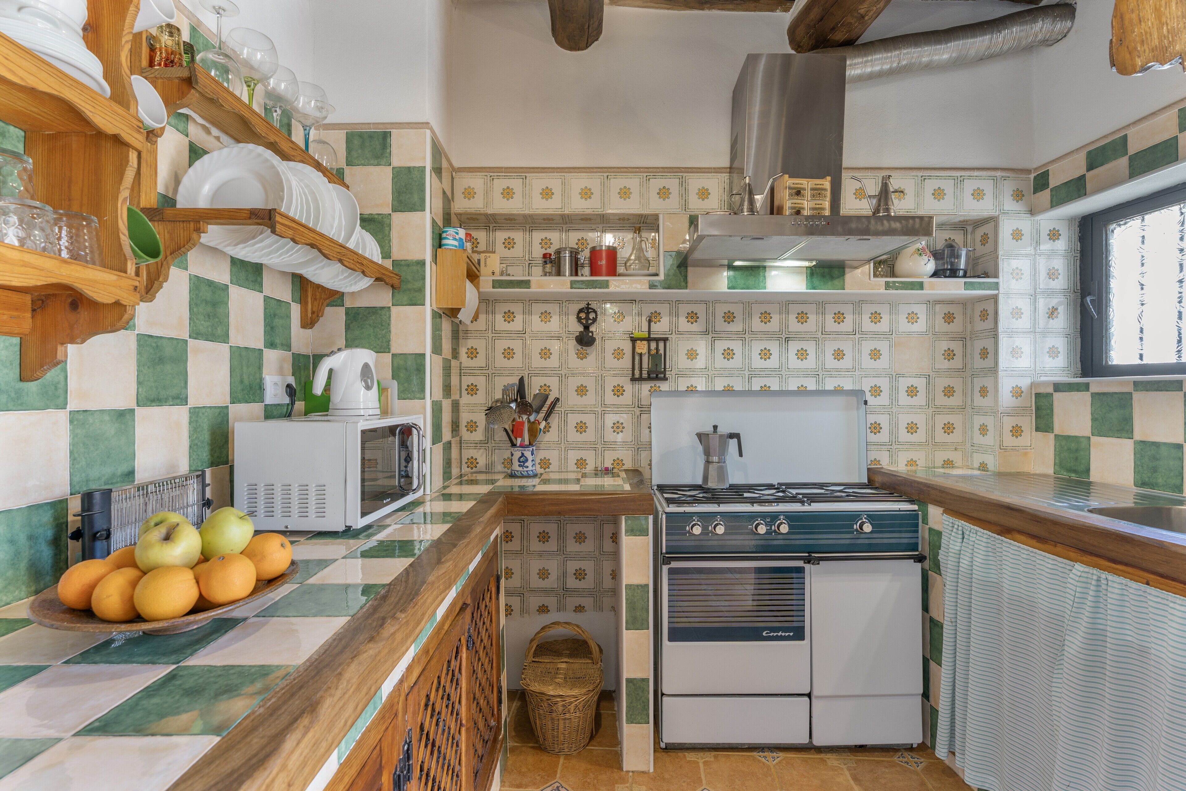 Une cuisine équipée d’une cuisinière, d’un four à micro-ondes et d’un panier de fruits posé sur le comptoir.