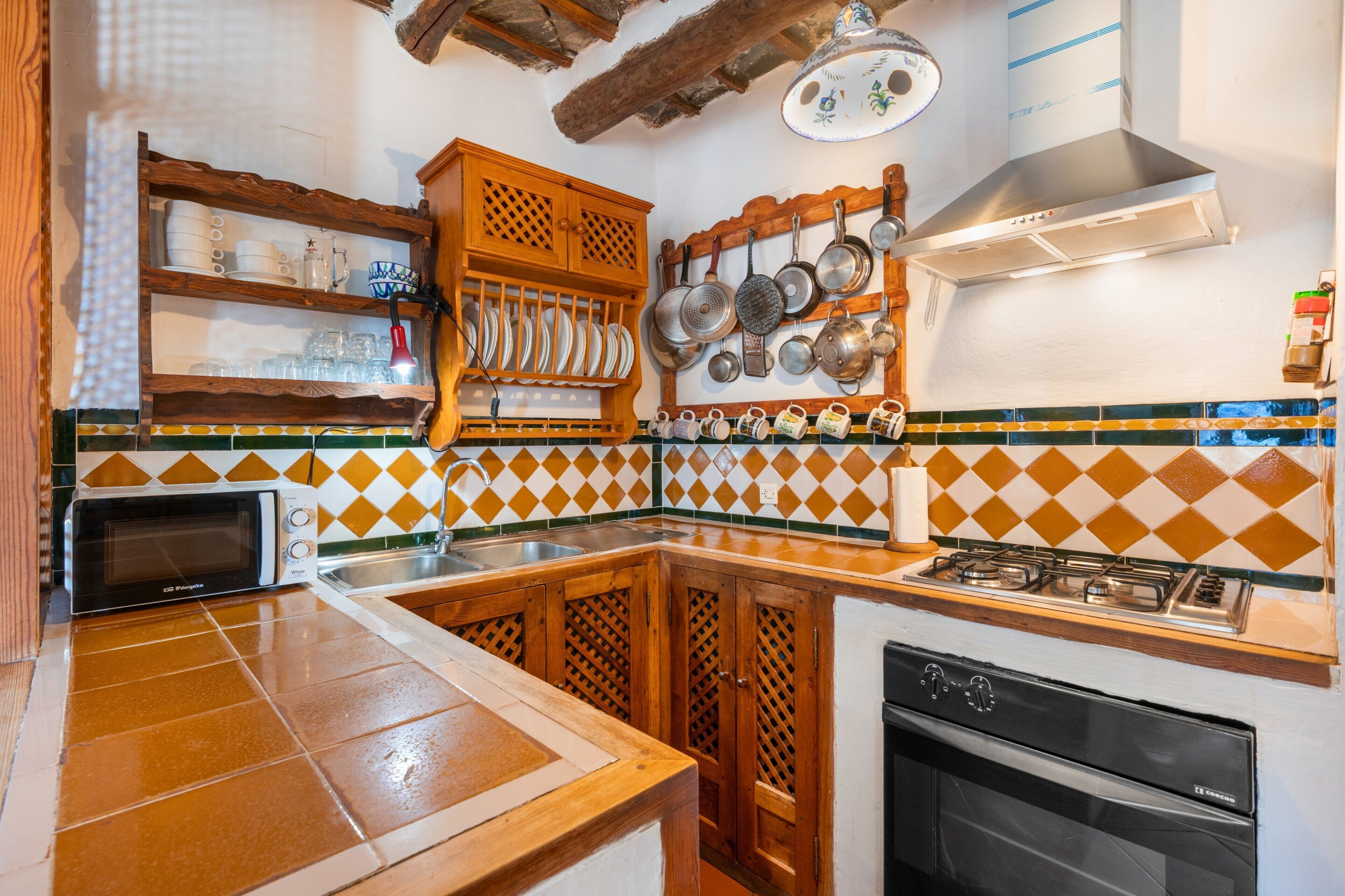 A kitchen with a microwave, stove, oven, and various dishes on shelves.