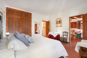 Ein Schlafzimmer mit einem großen Bett, einem Holzschrank, einem Esstisch mit Stühlen und einem kleinen Tisch mit Lampe.