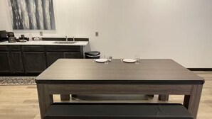 A modern kitchen with a dark wood dining table and bench, a built-in sink, and a countertop with various kitchen items. - Food Truck Court BNB w/breakfast & pool table (Carlsbad)