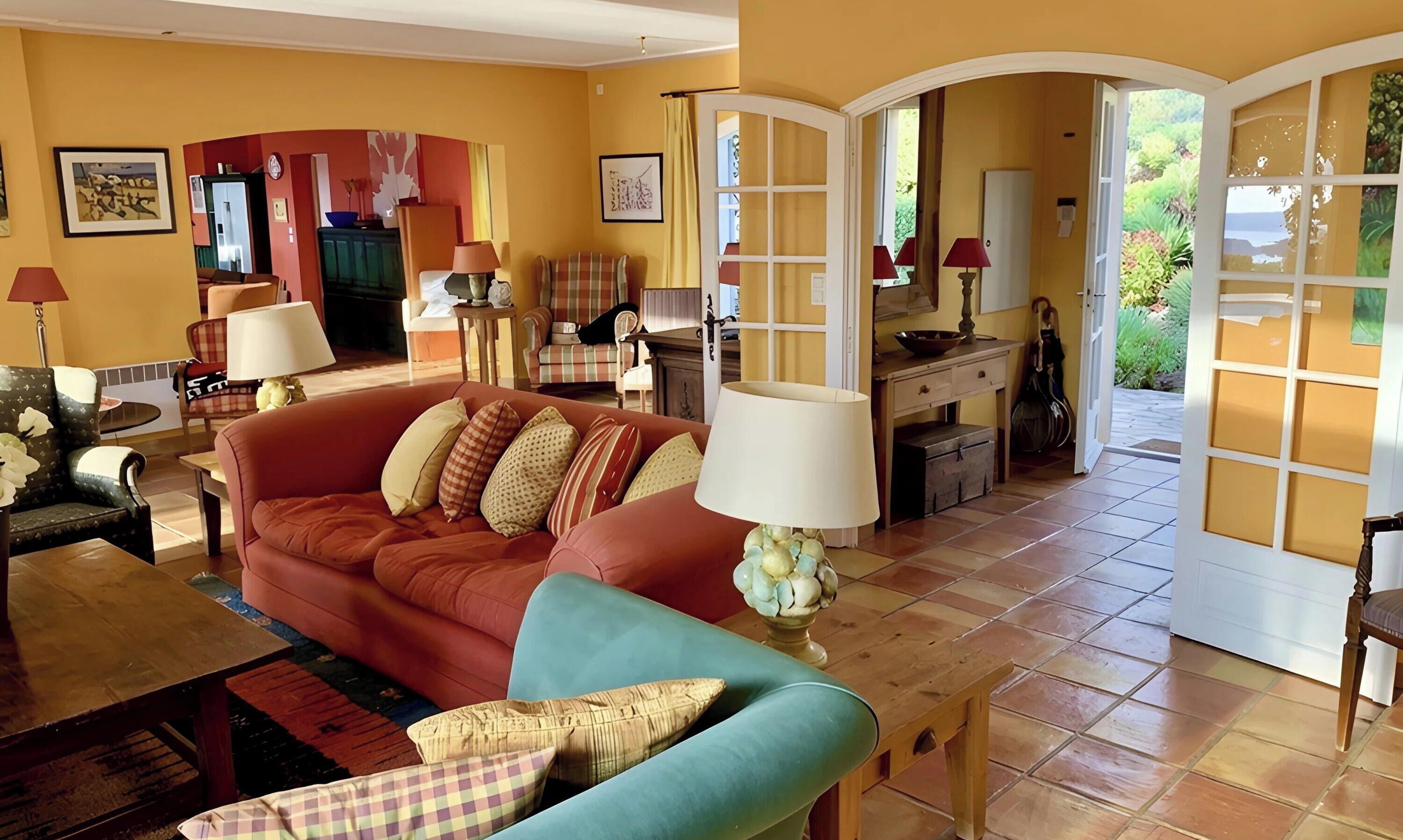 A living room with a red sofa, a blue armchair, and a dining area with a table and chairs.