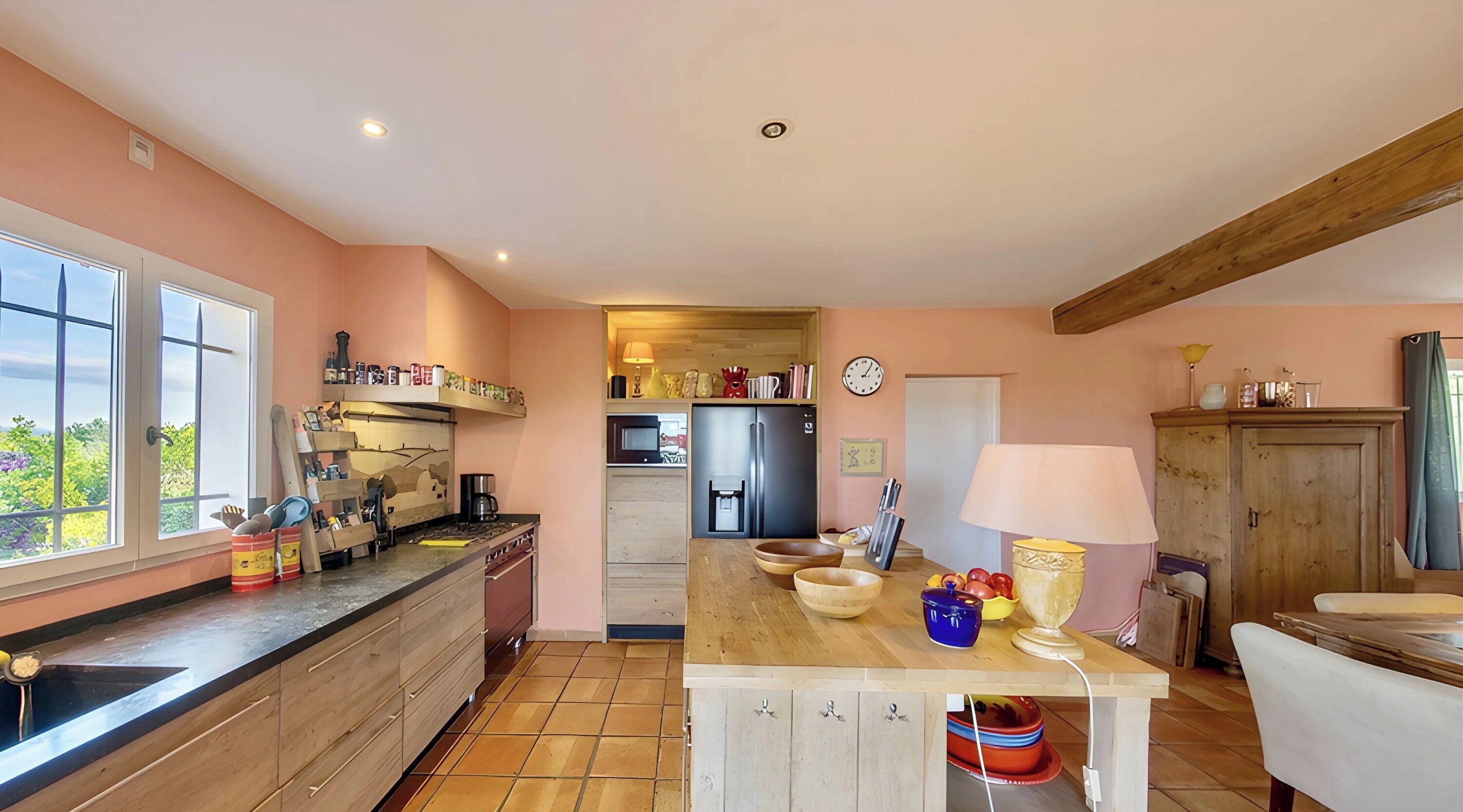 Une cuisine avec un plan de travail en bois, une cuisinière, un réfrigérateur et une table à manger avec une lampe.