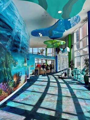 Ein großzügiger Innenbereich mit einer großen Wandmalerei von einer Unterwasserlandschaft, einer Rezeption und Sitzbereichen.
