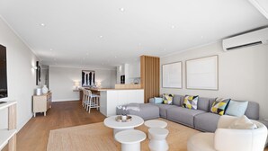 Een moderne woonkamer met een bank, salontafel, stoelen, een keukenhoek en een eethoek.