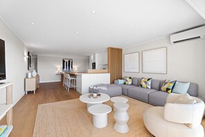 Una sala moderna con sofá, mesa de centro, sillas, una cocina y un comedor.