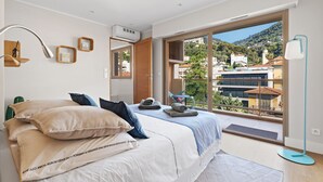Een slaapkamer met een groot bed, uitzicht op een stadsbeeld en een balkon.