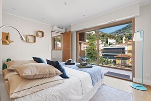 Un dormitorio con una cama grande, vistas a la ciudad y un balcón.