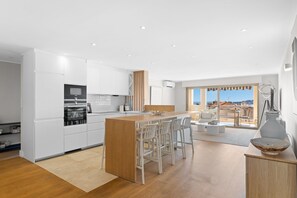 A modern kitchen with white cabinets, a wooden island, and bar stools. - Beaulieu Palace - Rooftop Vue Mer (Beaulieu-sur-Mer)