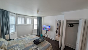 Ein Hotelzimmer mit einem Bett, einem Fernseher auf einem Schrank, einem Kleiderschrank und einer Tür zu einem Waschbereich.