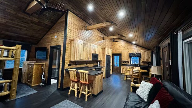 Interior de una cabaña de madera con cocina, comedor y sala de estar.