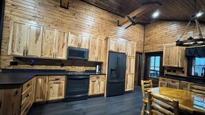 Una cocina con armarios de madera, un refrigerador negro, un microondas y una estufa.