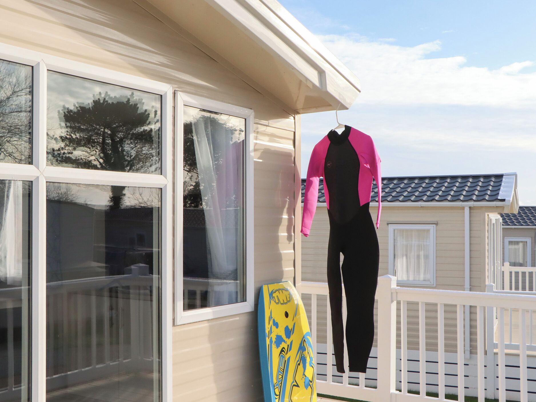 A house with large windows, a balcony, and a surfboard.