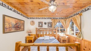 A rustic wooden room with a bed, a desk, and a window. - Hot Tub with Meadow Views! Pet Friendly! (Duck Creek Village)