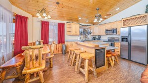A rustic kitchen with wooden furniture, a central island, and a stainless steel refrigerator. - Hot Tub with Meadow Views! Pet Friendly! (Duck Creek Village)